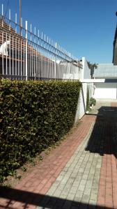 a hedge next to a fence and a sidewalk at Norte Hospedagem in Lages
