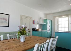 una cocina con una mesa de madera y un jarrón de flores en Galley Head Lightkeeper's Houses en Donoure