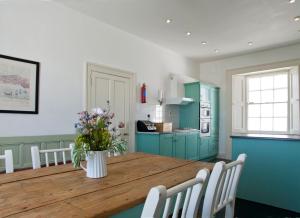 a kitchen with a wooden table with a vase of flowers at Galley Head Lightkeeper's Houses in Donoure