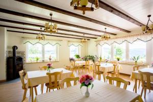 a dining room with tables and chairs and windows at Pension Berghof in Breitenbrunn