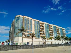 a large building with palm trees in front of it at OCEAN VIEW by Buenavilla in Arrecife