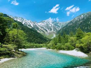 een rivier in een vallei met bergen op de achtergrond bij Guesthouse Hoshizora no Akari in Matsumoto