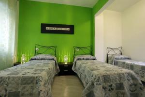 2 letti in una camera con pareti verdi di Appartamenti Romatour a Roma