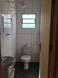 a bathroom with a toilet and a sink and a window at Casa do Disco Voador in São Thomé das Letras +2 photos