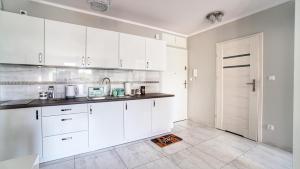 eine weiße Küche mit weißen Schränken und einer Tür in der Unterkunft Apartamenty GLOBAL BLIŻEJ MORZA 16/60 Kołobrzeg in Kołobrzeg