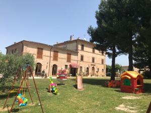 a yard with playground equipment in front of a building at Villa Montotto in Monterubbiano