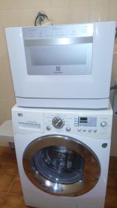 a washing machine with a microwave on top of it at Apartamento frente para o Mar ,50 m da praia , ar condicionado todos quartos in Guarujá