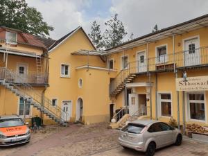 Zerbst的住宿－Pension Schloßwache-Zerbst，两辆汽车停在黄色建筑前面