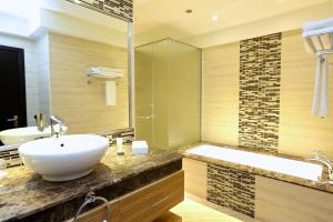 une salle de bain avec un lavabo, une baignoire et un miroir dans l'établissement Nehal Hotel, à Abu Dhabi 37 autres photos