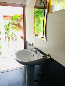 un bagno con lavandino, specchio e finestra di Sudu Neluma Home Stay a Polonnaruwa