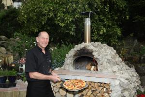 a man standing in front of a pizza oven at The Cables in Matlock