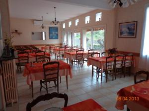 une salle à manger avec des tables, des chaises et un tissu de table rouge dans l'établissement Hôtel Hélios, à Lourdes