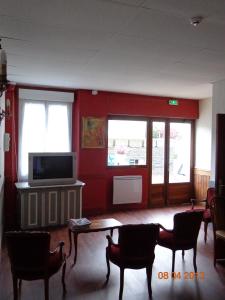 sala de estar con TV, mesa y sillas en Hôtel Hélios, en Lourdes