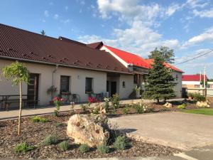 a building with a red roof and a rock at Kristály apartmanok in Kisvárda