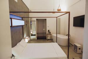 マンフレドーニアにあるDiomede Rooms - Manfredi Homes&Villasのベッドルーム(ベッド1台、バスタブ、テレビ付)