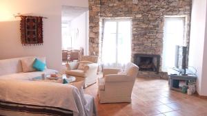 a living room with white furniture and a stone fireplace at Guesthouse Casa De La Roca , Kostos , Paros in Kóstos