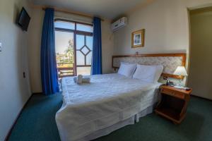 een slaapkamer met een groot bed en een raam bij Via Genova Parque Hotel in Serafina Corêa