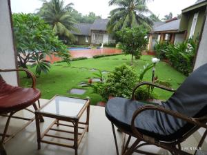 a balcony with chairs and a table and a yard at Anjuna Villa 32 in Anjuna