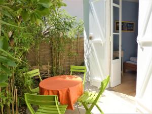 a patio with a table and green chairs at Charmante villa, 100m de la plage in Pyla-sur-Mer