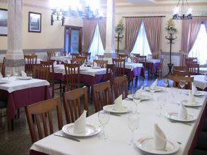 un comedor lleno de mesas y sillas con manteles blancos. en Hotel Los Hermanos, en Ocaña