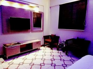 uma sala de estar com 2 cadeiras e uma televisão de ecrã plano em Diplomat Inn Hotel em Karachi