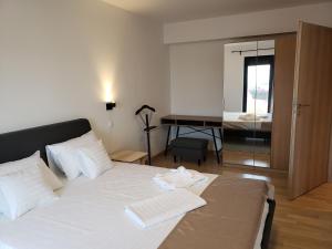 Urban Nest Apartment في بوخارست: غرفة نوم مع سرير مع ملاءات بيضاء ومكتب
