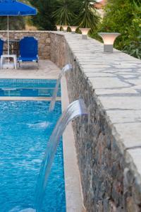 a pool with water shooting out of a retaining wall at Hotel Nostos in Nydri
