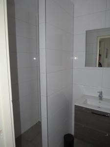 ein weißes Badezimmer mit Waschbecken und Spiegel in der Unterkunft appartement het Stolpje in Julianadorp + 19 Fotos