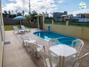 a patio with tables and chairs next to a pool at Flats Vieiras do Maragogi in Maragogi
