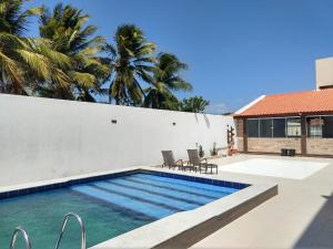 a swimming pool next to a white wall with palm trees at Hotel Costa do Delta in Tutóia