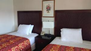 a hotel room with two beds and a lamp at Valley Hotel in Rosemead