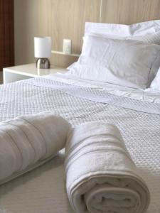 Una cama blanca con una toalla enrollada. en Ondina Apart Hotel en Salvador