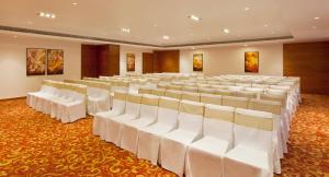a banquet hall with white chairs and tables at Gokulam Park Coimbatore in Coimbatore