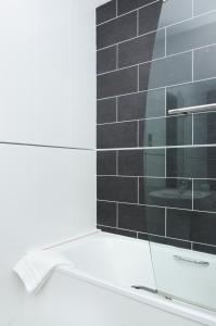 uma casa de banho com uma cabina de duche em vidro e uma parede em azulejo preto. em Beachcombers Hotel em Saint Helier