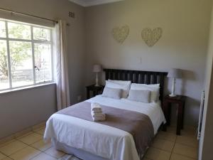 1 dormitorio con 1 cama grande y 2 corazones en la pared en Abendruhe Guest House, en Eshowe