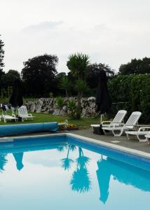 a swimming pool with two lawn chairs and umbrellas at Beachcombers Hotel in Saint Helier Jersey