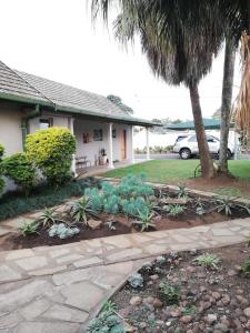 a garden in front of a house with palm trees at Abendruhe Guest House in Eshowe