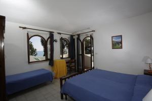 1 dormitorio con 2 camas, mesa y ventanas en Hotel La Giara, en Montauro