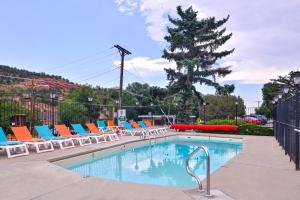 a swimming pool with lounge chairs and a tree at Villa Motel at Manitou Springs in Manitou Springs
