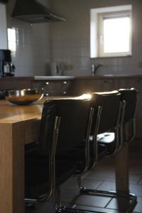 a kitchen with two black chairs at a wooden table at Hoeve "doodleger" in Vijlen +37 photos