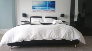 een slaapkamer met een groot wit bed met 2 lampen bij Tippy's Guesthouse in Newquay