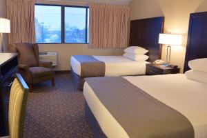 a hotel room with two beds and a chair at Riversage Billings Inn in Billings