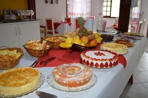 uma mesa com muitos bolos e frutas diferentes em Pousada Lapônia em Penedo