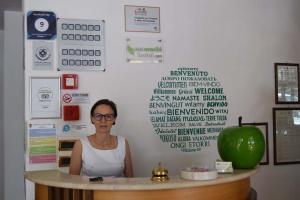 a woman standing in front of a counter with a sign on it at Eco-Hotel Edy in Chianciano Terme