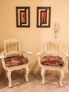dos sillas blancas sentadas en una habitación con fotos en la pared en Departamento Temporario Bahia Blanca en Bahía Blanca