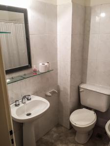 La salle de bains blanche est pourvue de toilettes et d'un lavabo. dans l'établissement Departamento Temporario Bahia Blanca, à Bahía Blanca