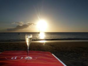 una copa de vino sentada en una mesa en la playa en Cote Plage, en Le Carbet