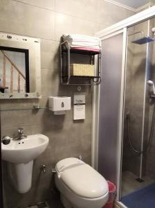 een badkamer met een toilet, een wastafel en een douche bij 台南昱家小巷包棟民宿 in Anping