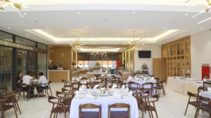a restaurant with white tables and chairs and people sitting at tables at Dai Viet Hotel in Thanh Hóa