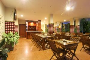 a restaurant with wooden tables and chairs and a bar at Manggar Indonesia Hotel in Kuta
